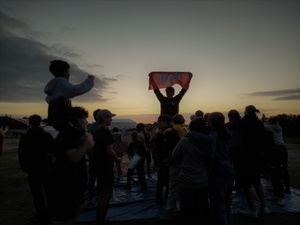 Eine Falkenfahne vor Sonnenuntergang, hochgehalten von Teilnehmenden